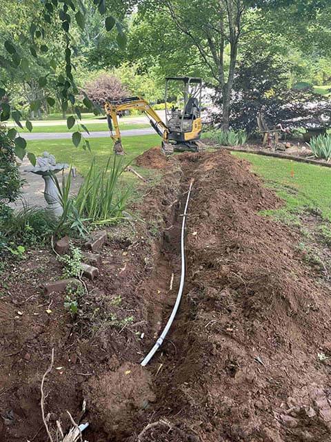 Excavator digging a trench for new septic line installation
