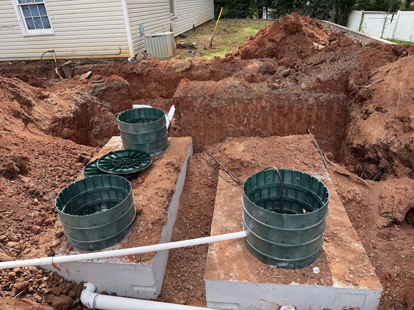 Drainfield trench prepared for pipe installation in red clay soil